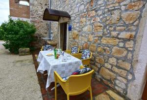 ポレッチにあるKlimatisierte Wohnung in Tar mit Garten, Terrasse und Grillの黄色い椅子と石の壁のあるテーブル