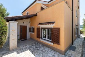 uma casa com persianas castanhas ao lado em Ferienhaus in Pomer mit privatem beheizten Pool und Meerblick em Pomer