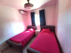 two beds in a small room with red sheets at Comfortable Apartament in Los Paredones