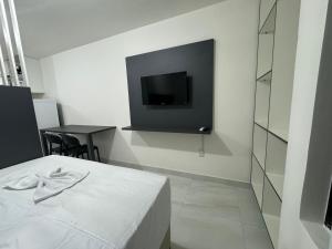 1 dormitorio con 1 cama y TV en la pared en Flat a 400 metros da praia!, ótima localização. en Cabedelo