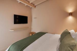 a bedroom with a bed with a tv on the wall at Antipoda Hotel Boutique in Medellín