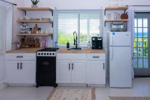 cocina con armarios blancos, fogones y nevera en Tulixx Cayman Villa 