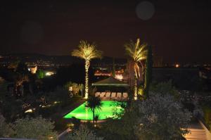 - une vue sur une piscine bordée de palmiers la nuit dans l'établissement Stilvolle Wohnung in Toscolano Maderno mit Kleiner Terrasse, à Toscolano Maderno