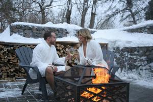 a man and woman sitting around a fire pit at La Belle Excuse in Saint-Joachim