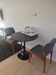 a table with two chairs and a table with two cups on it at Avon Apartments in Hamilton