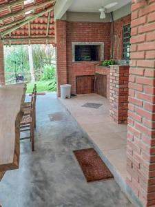 eine Terrasse mit Kamin und Ziegelwand in der Unterkunft Cabana com cachoeira no quintal in Antônio Carlos