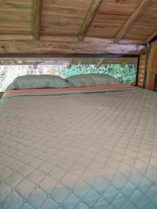 ein großes Bett in einem Zimmer mit Holzdecke in der Unterkunft Cabana com cachoeira no quintal in Antônio Carlos