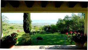 una ventana con vistas a un patio con flores en Ferienwohnung für 4 Personen ca 80 qm in Castiglione d'Orcia, Toskana Provinz Siena, en Campiglia dʼOrcia
