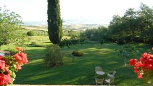 un patio verde con 2 mesas y sillas en el césped en Ferienwohnung für 4 Personen ca 80 qm in Castiglione d'Orcia, Toskana Provinz Siena, en Campiglia dʼOrcia