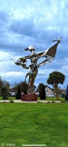 a statue of a woman with a bird in a field at La Bonne Brise in Grandcamp-Maisy