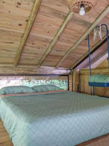 Bett in einem Zimmer mit Holzdecke in der Unterkunft Cabana com cachoeira no quintal in Antônio Carlos