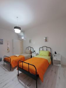 una camera con 2 letti con lenzuola arancioni e gialle di La Dimora degli Artisti - Bologna a Bologna