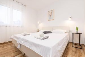 Un dormitorio blanco con una cama blanca grande con toallas. en Villa Ema und Ana, en Pula