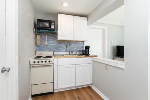 eine weiße Küche mit einem Herd und einer Mikrowelle in der Unterkunft Hampton Beach Seaside Villa Unit 1 in Hampton