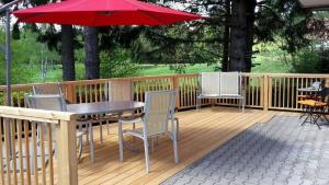 a wooden deck with a table and chairs and an umbrella at Ferienhaus in Milná mit Kleiner Sauna in Lojzova Paseka