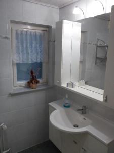 bagno bianco con lavandino e specchio di Ferienhaus in Breitenstein mit Grill und Garten - b48748 a Breitenstein