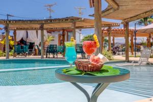 uma mesa com 2 cocktails e uma cesta de frutas em Pousada Praia Bela em Ilhéus