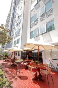 a group of tables and chairs with umbrellas in front of a building at Hotel Runcu Miraflores in Lima