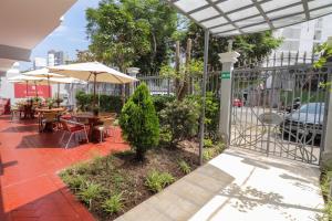 a patio with tables and chairs and an umbrella at Hotel Runcu Miraflores in Lima
