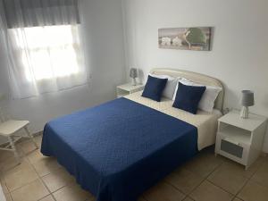 a bedroom with a blue bed and a window at Apartamento Tabaiba in Tamaduste