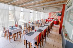 a restaurant with white tables and chairs and windows at Hotel Boutique Runcu Miraflores in Lima
