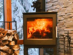 a stove with a fire in it next to a window at Karuizawa Forest Seasons Villa in Karuizawa