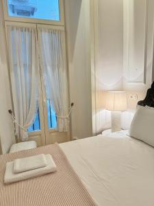a white bedroom with a bed and a window at Charming apartment on Rua Augusta in Lisbon