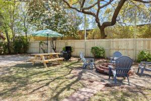 un patio con sillas, una mesa de picnic y una sombrilla en The Azalea House, en Charleston