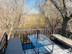 a glass table and bench on a balcony with trees at Retief Guest Farm in Kroonstad