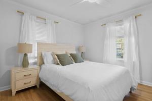 1 dormitorio blanco con 1 cama blanca y 2 ventanas en The Azalea House, en Charleston