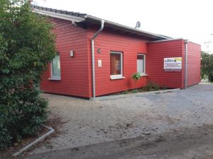 un edificio rojo con un cartel en el costado en Ferienhaus am kleinen See mit Steg, Garten und Terrasse en Twist
