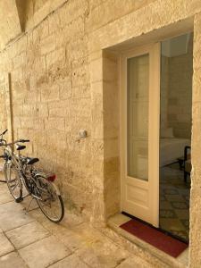una bicicleta estacionada junto a una pared de piedra con una puerta en Antica casa, en Vernole