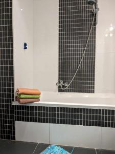 - Baño con bañera y estante con toallas en Appartement avec jardin, en Visé