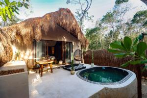 a small hut with a swimming pool in front of it at The Yellow Nest Tulum in Tulum