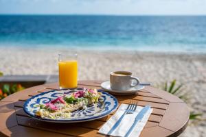 Hotel Dos Playas Faranda Cancún في كانكون: طاولة مع طبق من الطعام وكوب من عصير البرتقال