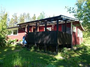 uma casa vermelha com uma cerca preta à frente. em Typisches Holzhaus mit überdachter Terrasse auf weitläufigen Grundstück in einem Waldgebiet am See em Hallaryd