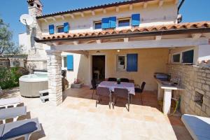 un patio con tavolo, sedie e una casa di Ferienhaus in Kavran mit Terrasse und Grill a Kavran