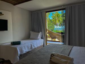 1 dormitorio con 2 camas y vistas al océano en Vila Hayô en Passo de Camarajibe