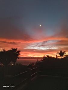 a sunset over the ocean with a fence and trees at HACIENDA LA CENTENARIA,CASAS RURALES in El Paso