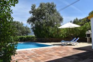 een zwembad met een parasol en een stoel bij Ferienhaus mit Privatpool für 4 Personen ca 120 qm in Corumbela, Andalusien Costa del Sol in Sayalonga