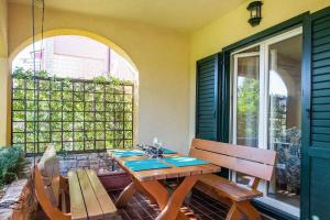 eine Terrasse mit einem Holztisch und 2 Bänken in der Unterkunft Strandnahe Wohnung mit überdachter Terrasse und Garten in Fažana