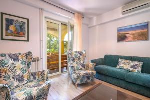 ein Wohnzimmer mit einem Sofa und 2 Stühlen in der Unterkunft Strandnahe Wohnung mit überdachter Terrasse und Garten in Fažana