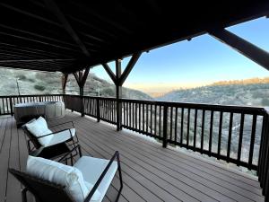 a deck with chairs and tables on a balcony at NEW & Luxurious House, hot tub & amazing views in Lake Arrowhead