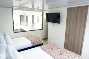 a hotel room with two beds and a television at Hotel Sky Blue in Manizales