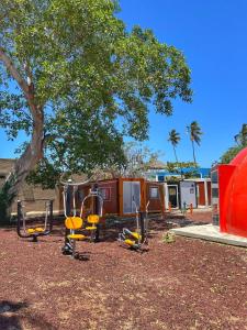 une aire de jeux avec des balançoires et un arbre dans une cour dans l'établissement Yellow house 6 minutos de playa, à Barra de Navidad