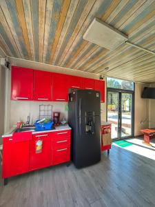 - une cuisine avec des placards rouges et un réfrigérateur noir dans l'établissement Yellow house 6 minutos de playa, à Barra de Navidad