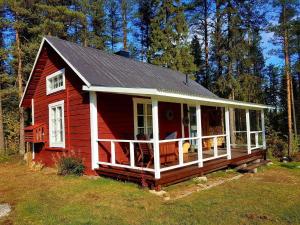 a red house with a porch on a field at Charmantes Ferienhaus in der Wildnis Lapplands in Blattniksele