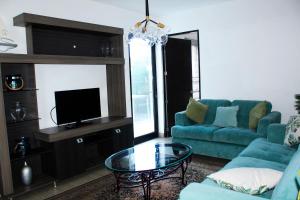 The Luxury Apartment في سان سلفادور: غرفة معيشة مع أريكة زرقاء وتلفزيون