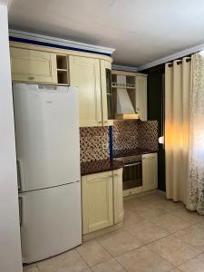 uma cozinha com armários brancos e um frigorífico branco em Xplore Xpress • Penthouse em Tirana