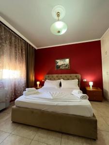 een slaapkamer met een groot bed met een rode muur bij Xplore Xpress • Penthouse in Tirana